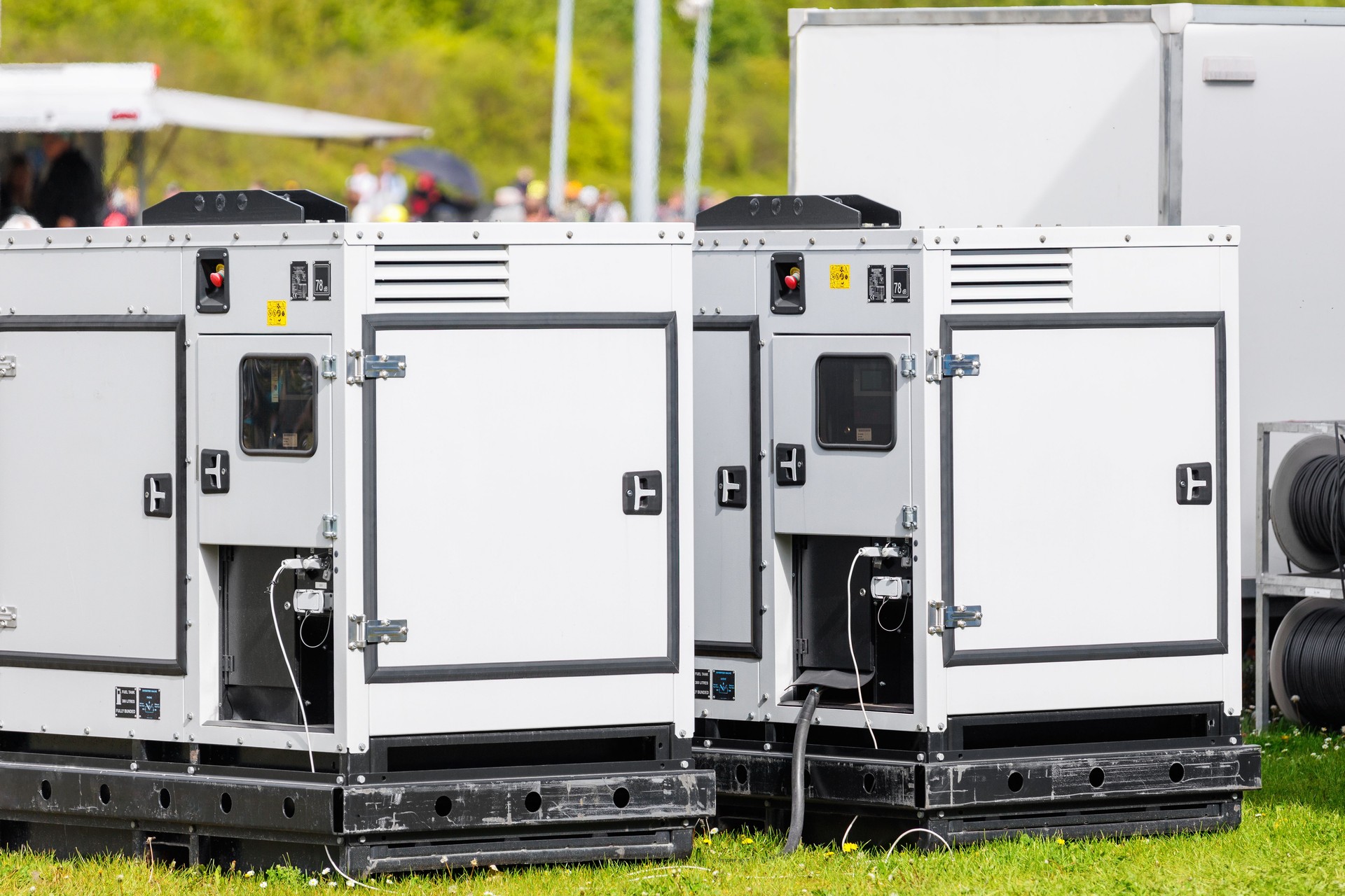 Set two large portable industrial power fuel generator green lawn at commercial event outdoors clear blue sky background. Mobile electricity supply energy plant unit backup equipment rent service