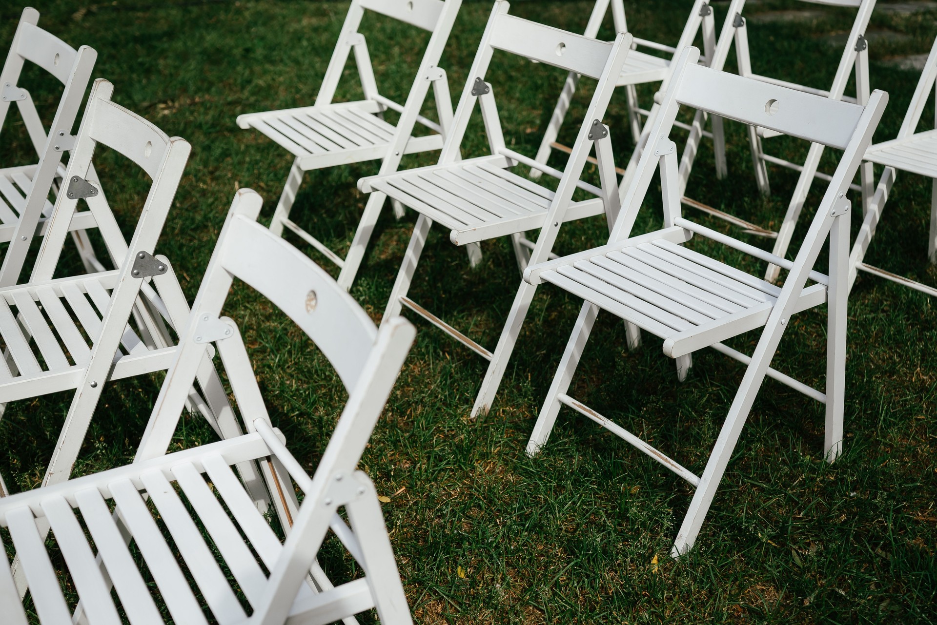 Empty White Folding Chairs Arranged on Grass